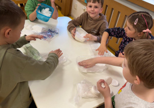 Dzieci wykładają pojemniki watą.