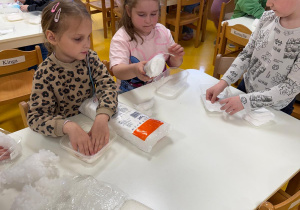 Dzieci wykładają pojemniki watą.