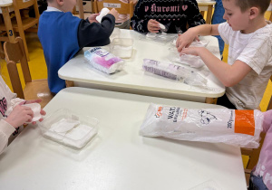 Dzieci wykładają pojemniki watą.