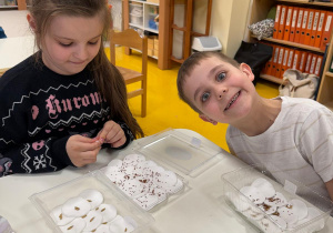 Dzieci układają ziarenka na wacie.