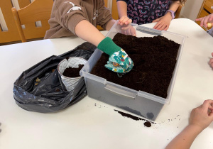 Chłopiec sypie łopatką ziemię.