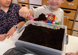 Chłopiec sypie łopatką ziemię.