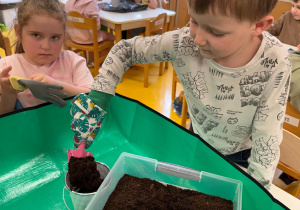 Chłopiec sypie ziemię.