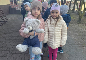 Dziewczynki stoją z misiem w ręku gotowa na wizytę w bibliotece.