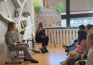 Panie z biblioteki czytają dzieciom książkę.