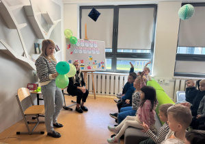 Pani trzyma w ręku balony, w których ukryte są zagadki.