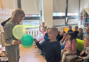 Chłopiec przebija balon z zagadką.