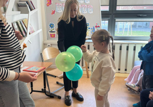 Dziewczynka przebija balon z zagadką.