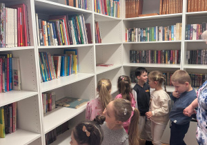Dzieci oglądają książki, które są w bibliotece.