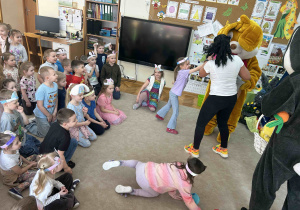 Dzieci siedząc na dywanie patrzą na zająca.