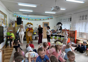 Dzieci czmychają przed paniami, które polewają wodą.