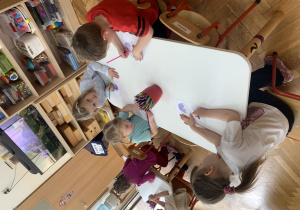 Przedszkolaki kolorują kredkami Tremka.