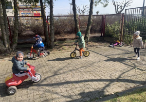 Pobyt dzieci z grupy Kropelek na placu zabaw - jazda na rowerkach biegowych.
