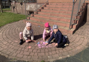 Dziewczynki rysują kredą na kostce.