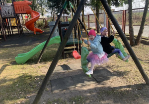 Dziewczynki podczas zabawy na huśtawce.