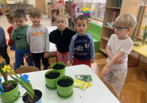 Czterolatki przy stole z donicami.