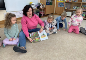 Pani czyta i pokazuje ilustracje w książce.