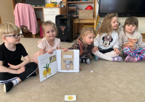 Dziewczynka pokazuje ilustracje z książki - ,,Kolorowy potwór - Doktor od emocji".