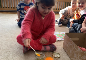 Dziewczynka przelewająca magiczny płyn do słoika z olejem.