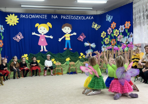 Dziewczynki kucają w tańcu.