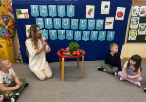 Nauczyciel trzyma w ręku pomidorki koktajlowe.