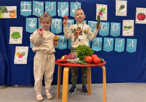 Dzieci trzymają w ręku owoce i warzywa.