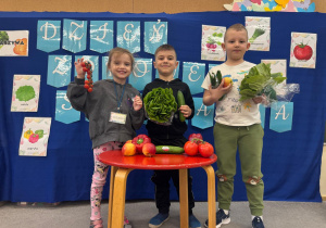 Dzieci trzymają w ręku warzywa i owoce.