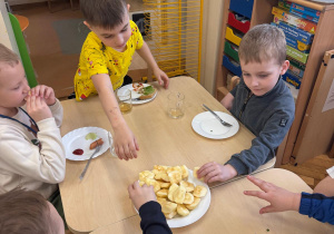 Chłopcy częstują się jabłkiem.