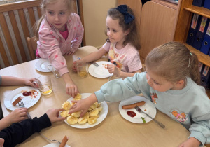 Dziewczynki biorą jabłkaa z talerza.