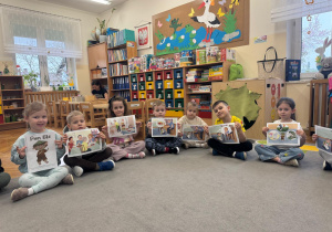 Dzieci pokazują ilustracje z opowiadania czytanego przez nauczyciela.