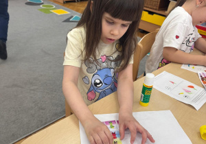 Dziewczynka wkleja postać Pana Ble do książeczki.