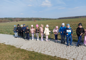 Przedszkolaki stoją w szeregu z kijkami.