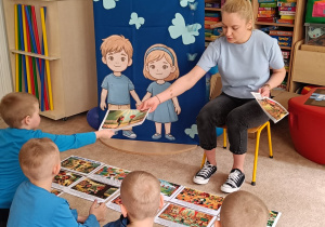 Nauczyciel podaje chłopcu ilustracje.