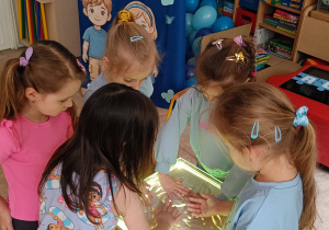 Dziewczynki rysują palcami na piasku.