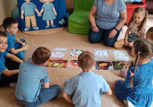 Nauczyciel opowiada dzieciom siedzącym na dywanie.