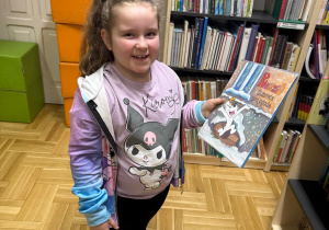 Dziewczynka trzyma książkę w rękach.