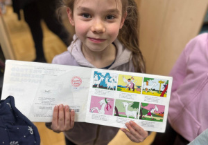 Dziewczynka trzyma komiks w rękach.