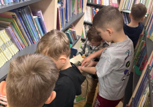 Dzieci oglądają książki na półkach.