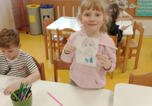 Dziewczynka pokazuje pokolorowaną postać Tremka.