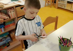 Chłopiec wycina nożyczkami.