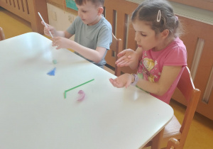 Dzieci dmuchają kolorowe piórka.