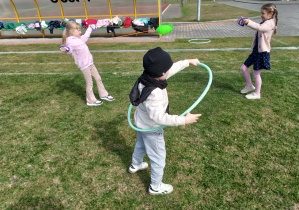 Dzieci korzystają ze sprzętów gimnastycznych na trawie.