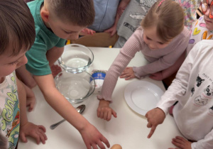 Dzieci sprawdzają czy jajko ugotowane szybciej się kręci niż surowe.