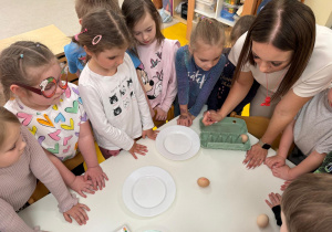 Pani prezentuje dzieciom eksperyment z gotowanym i surowym jajkiem.