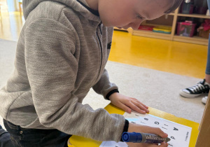 Chłopiec zaznacza literkę j.