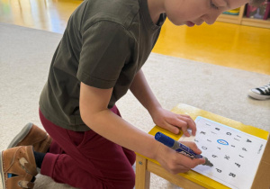 Chłopiec zaznacza literkę j.