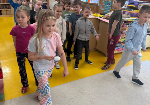 Dzieci ścigają się z jajkami na łyżkach.