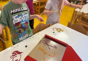 Dzieci układają ze sznurków literkę j.