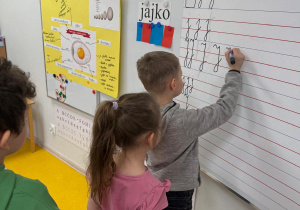 Chłopiec zapisuje literkę na tablicy.