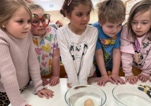 Dzieci obserwują, że w zwykłej wodzie jajko opada na dno.